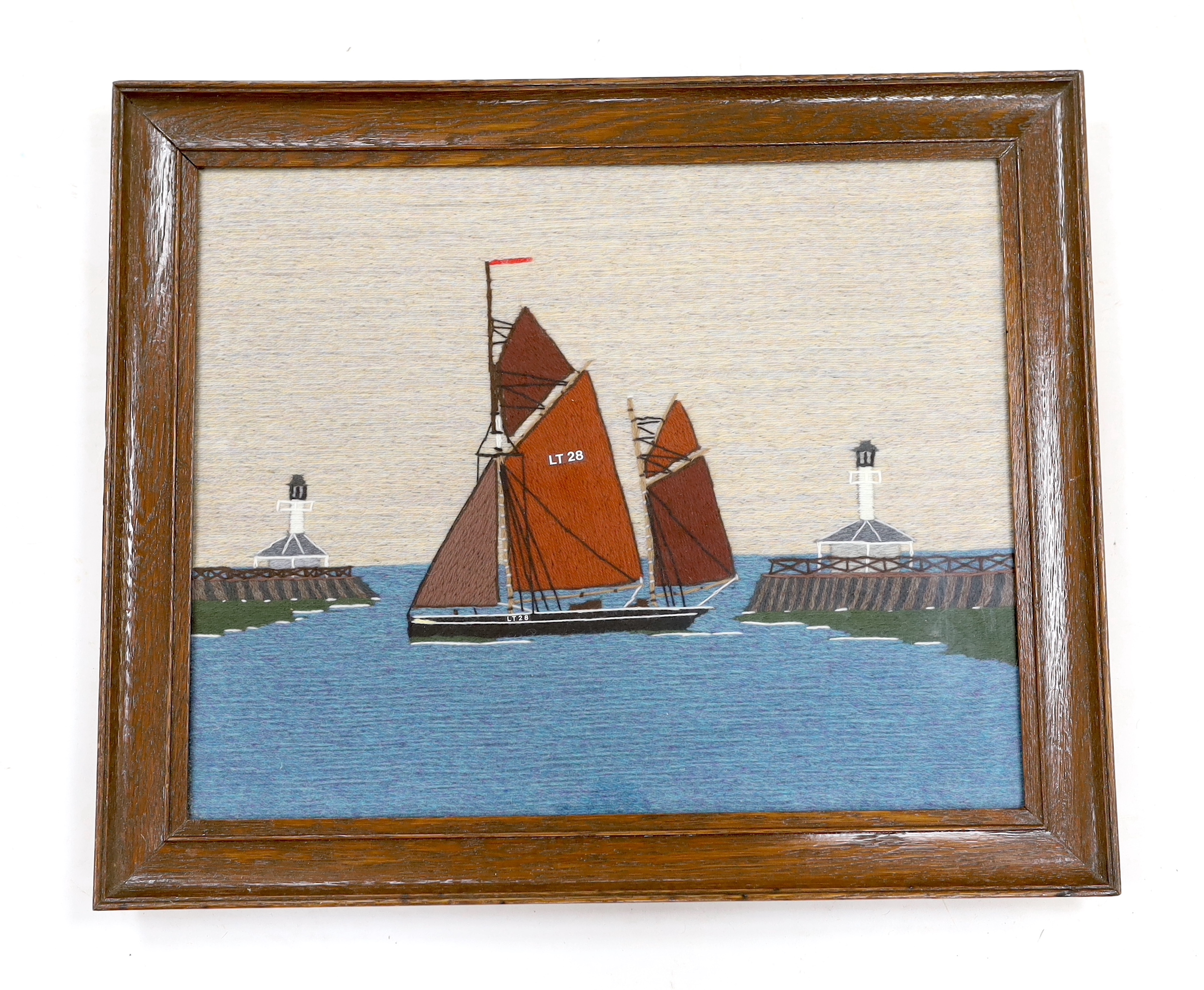 A long stitch wool work embroidery of ‘The Lowestoft Ketch Susie LT28’, in a harbour mouth, 20th century, 35.5 x 44cm.